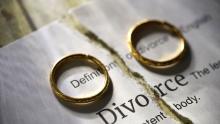 Two wedding rings placed on a torn divorce certificate.