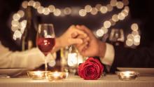 Two people in love are holding hands at a restaurant table.